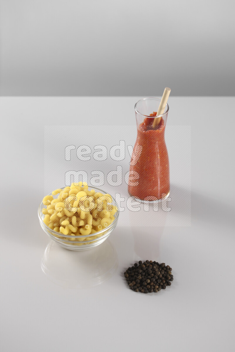 معكرونة مع صلصة طماطم مع مكونات متنوعة من الطماطم والثوم والريحان والفلفل الأحمر والفلفل الأسود والفلفل الأبيض وأوراق الغار والهيل وسنابل القمح على خلفية رمادية