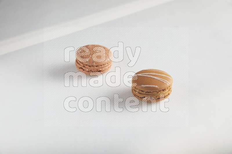 45º Shot of of two assorted Brown Irish Cream, and Brown Hazelnuts macarons on white background