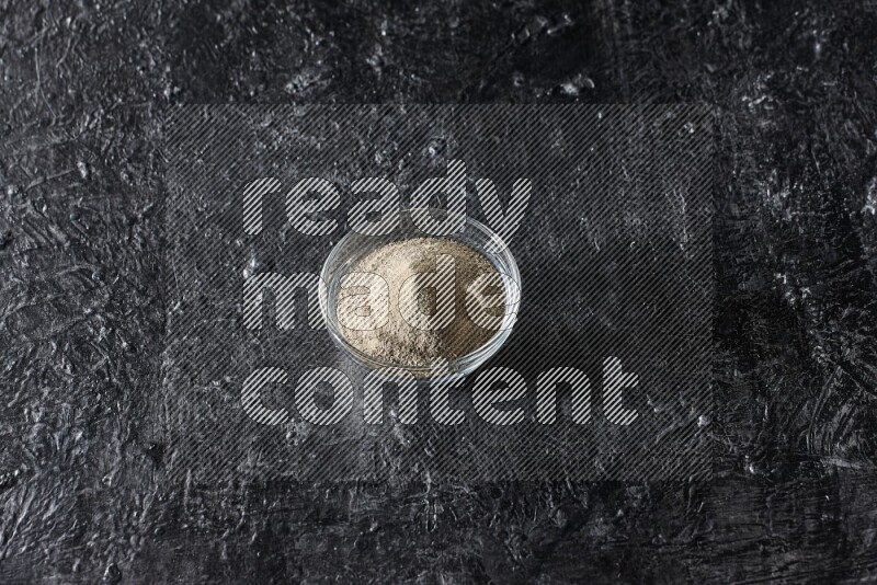 وعاء زجاجي مملوء بمسحوق الفلفل الأبيض على أرضية سوداء