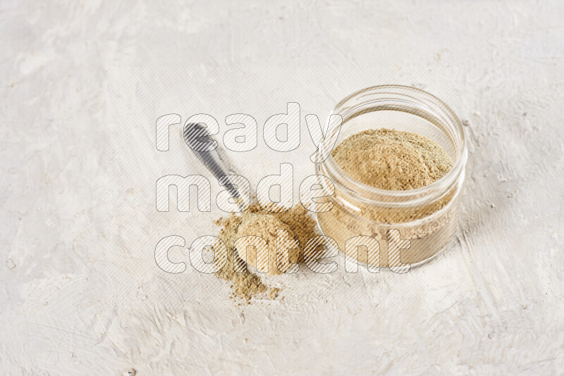 A glass jar full of ground ginger powder on white background