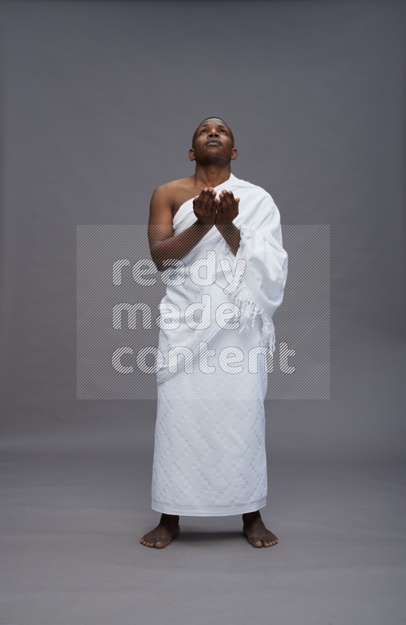 A man wearing Ehram Standing dua'a on gray background