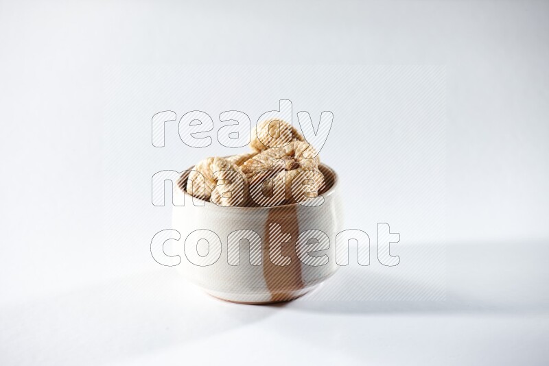 A beige ceramic bowl full of dried figs on a white background in different angles