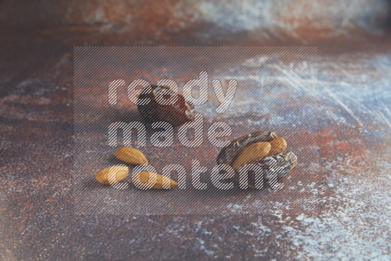 two almond stuffed madjoul dates on a rustic reddish background