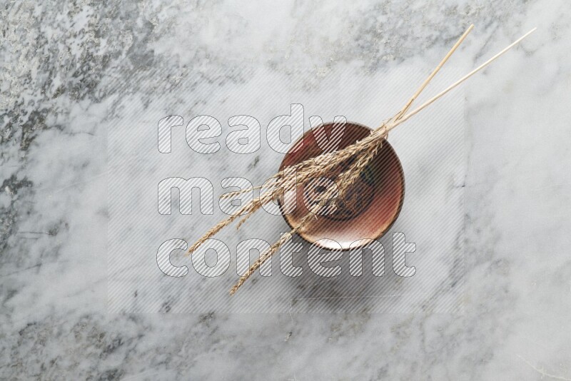 Wheat stalks on decorative pottery plate on grey marble background