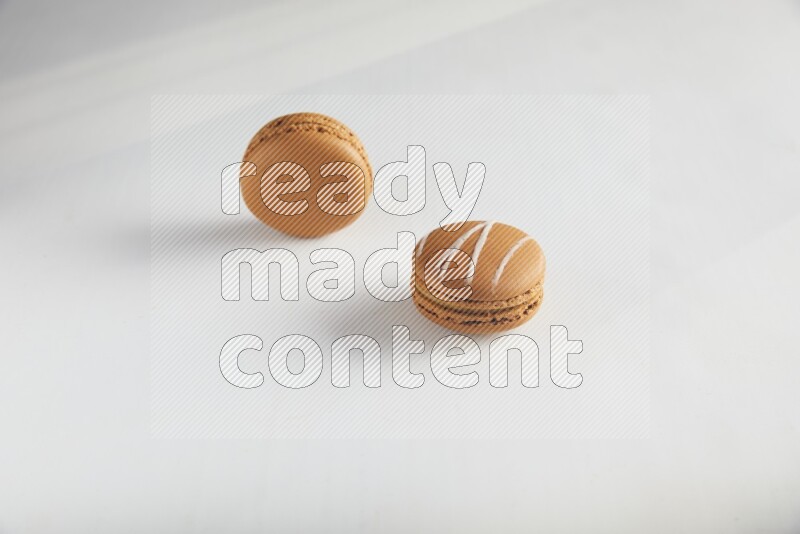 45º Shot of of two assorted Brown Irish Cream, and Brown Maple Taffy macarons  on white background