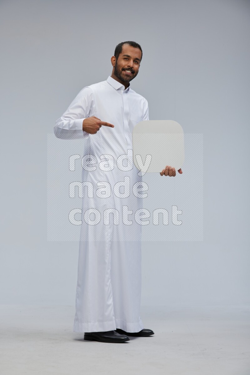 Saudi man wearing Thob standing holding social media sign on Gray background