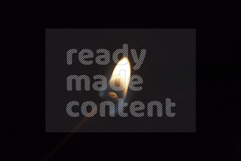 A burning matchstick isolated on dark backdrop