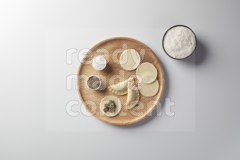 two closed sambosas and one open sambosa filled with meat while flour, salt, and black pepper aside in a wooden dish on a white background