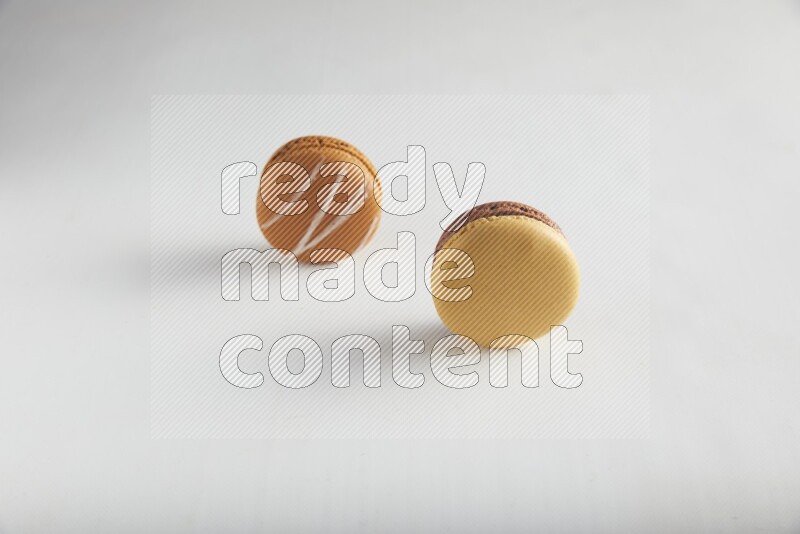 45º Shot of of two assorted Brown Irish Cream, and Yellow, and Brown Chai Latte macarons on white background