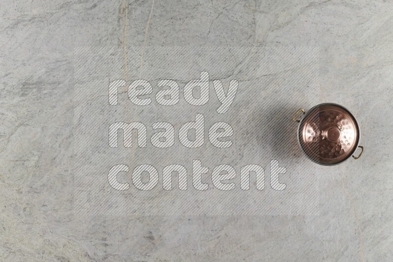 A small copper pot on grey marble background