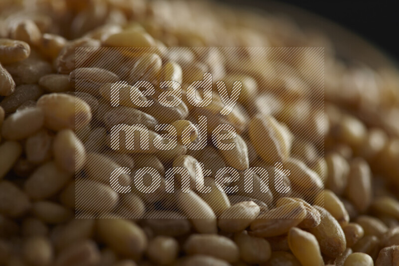 Hulled wheat in a glass jar on black background