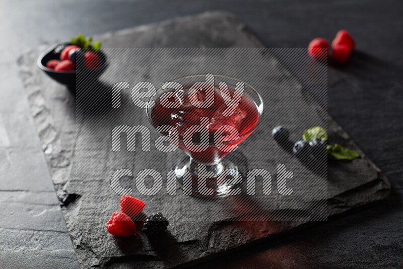 A glass of mixed berries juice on black background