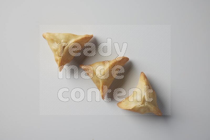 Three fried sambosa from a top angle on a white background