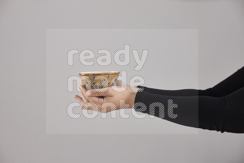 A woman in black abaya holding different pottery essentials in different positions