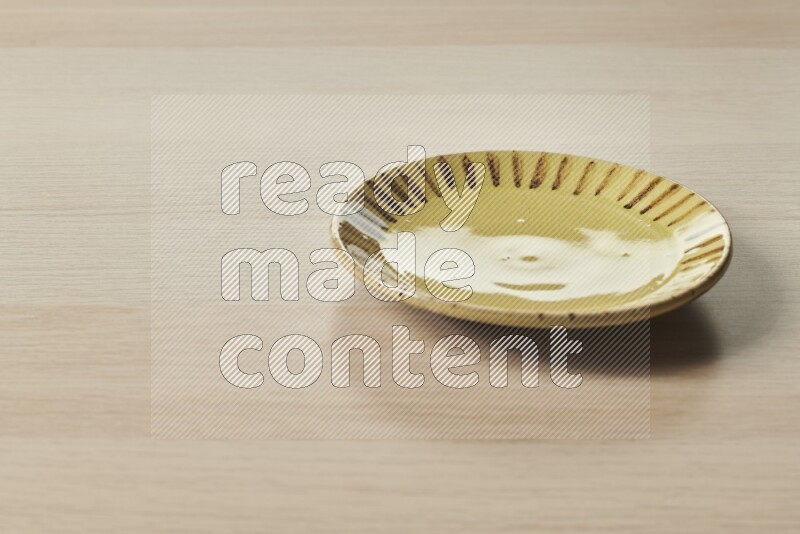 A multicolored pottery plate on light wooden background