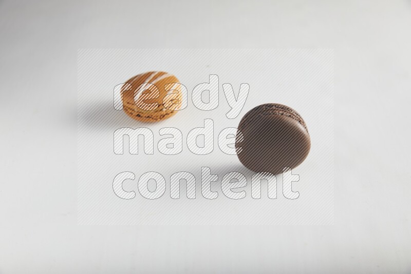 45º Shot of of two assorted Brown Irish Cream, and Brown Dark Chocolate macarons on white background