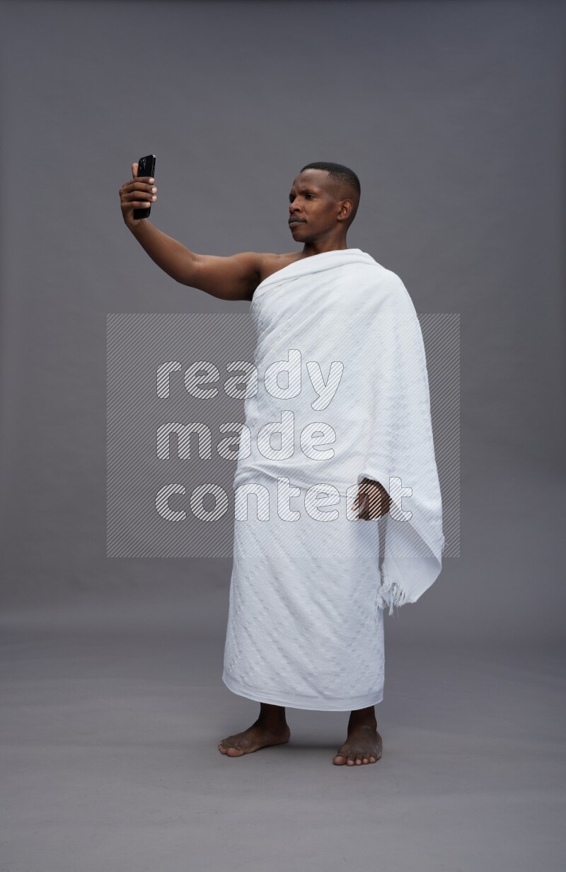 A man wearing Ehram Standing taking selfie on gray background