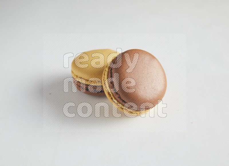 45º Shot of two Yellow and Brown Chai Latte macarons on white background
