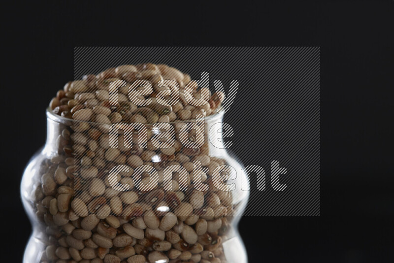 Black-eyed peas in a glass jar on black background