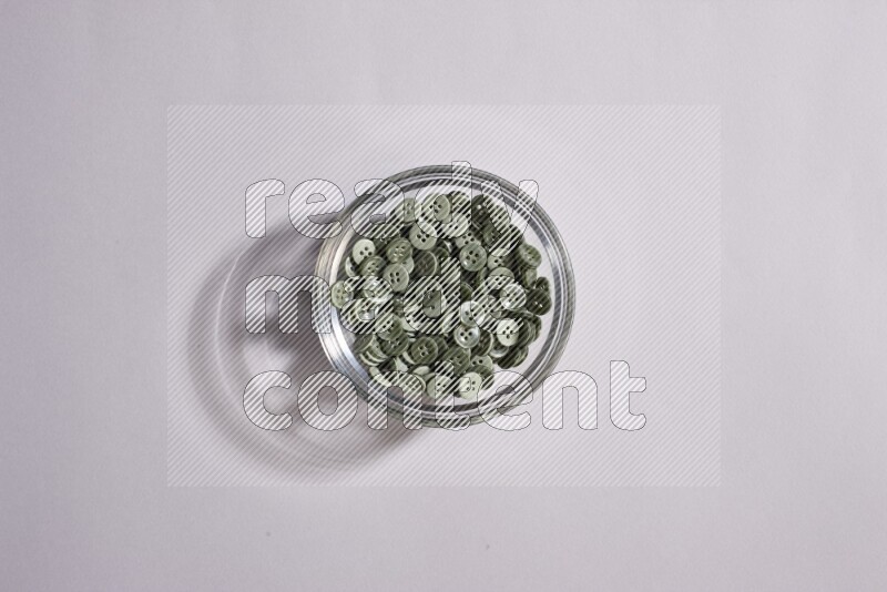 Colored buttons in a glass bowl on grey background