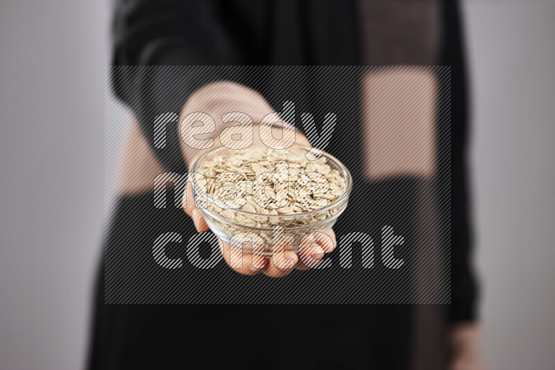 Woman in abaya holding different kinds of legumes in different positions