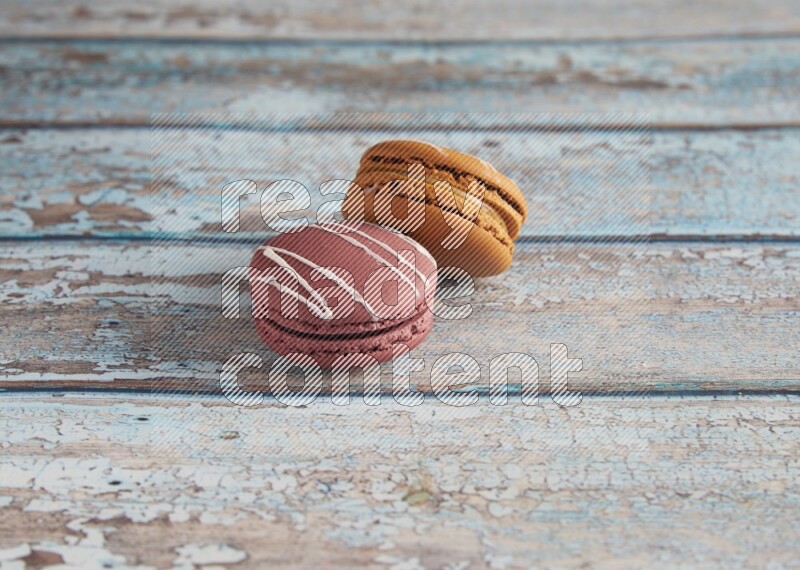 45º Shot of of two assorted Brown Irish Cream, and Red Poppy Flower macarons  on light blue background