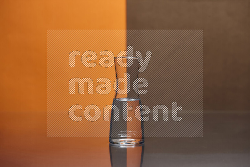 The image features a clear glassware filled with water, set against orange and brown background