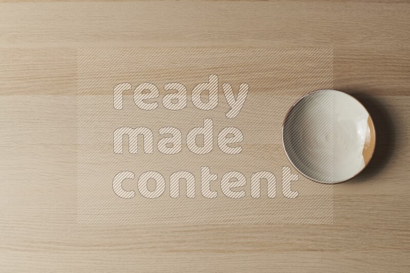 A multicolored pottery plate on light wooden background