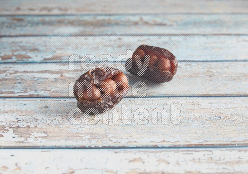 two hazelnuts stuffed madjoul dates on a light blue wooden background