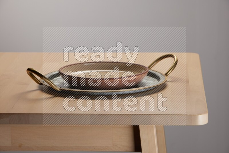 multicolored plate placed on a rounded stainless steel tray with golden handels on the edge of wooden table