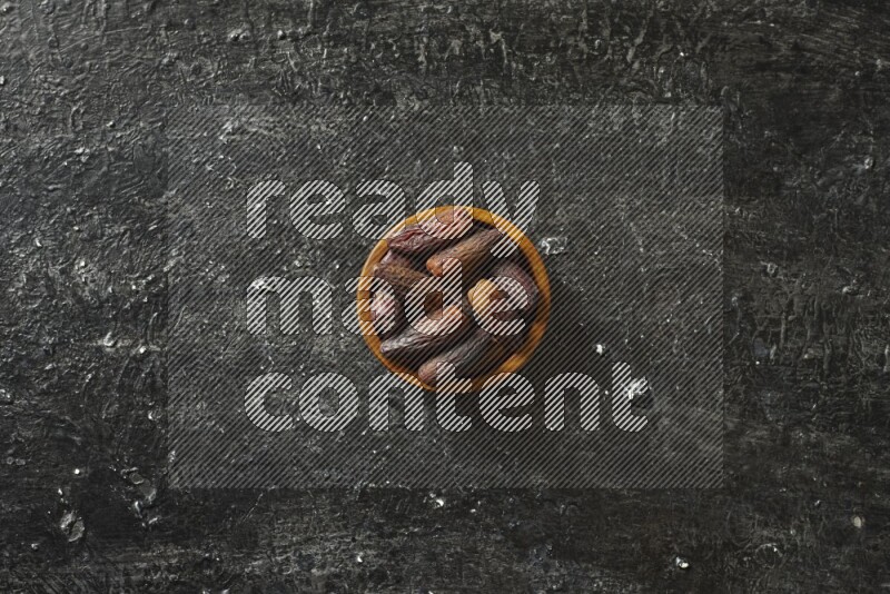 Dates in wooden bowls in a dark setup