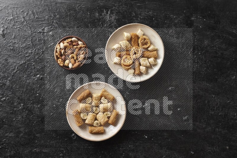 Oriental sweets in pottery plates with nuts in a dark setup