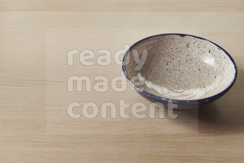A multicolored pottery bowl on light wooden background