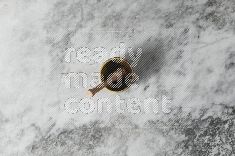 Multicolored pottery cup with wooden honey dipper in it on grey marble background