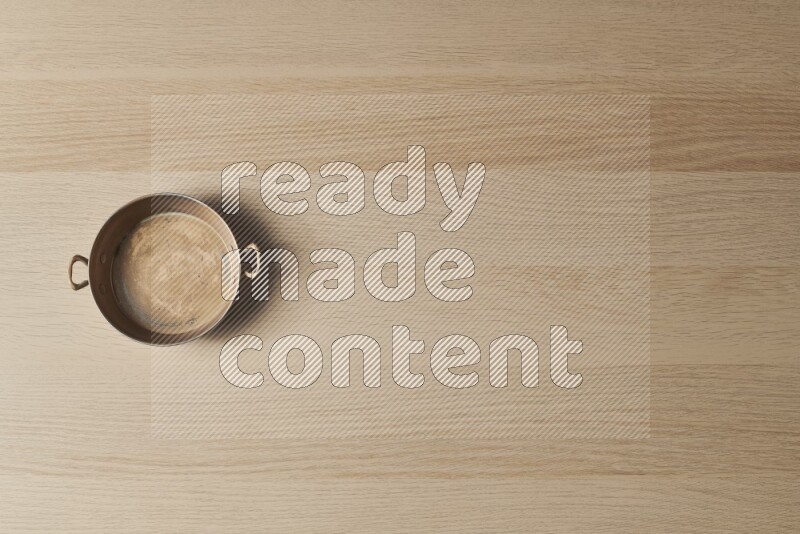 A small copper pan on light wooden background