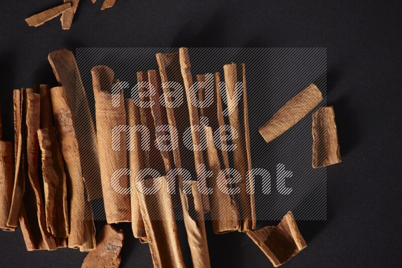 Cracked cinnamon sticks on a black background