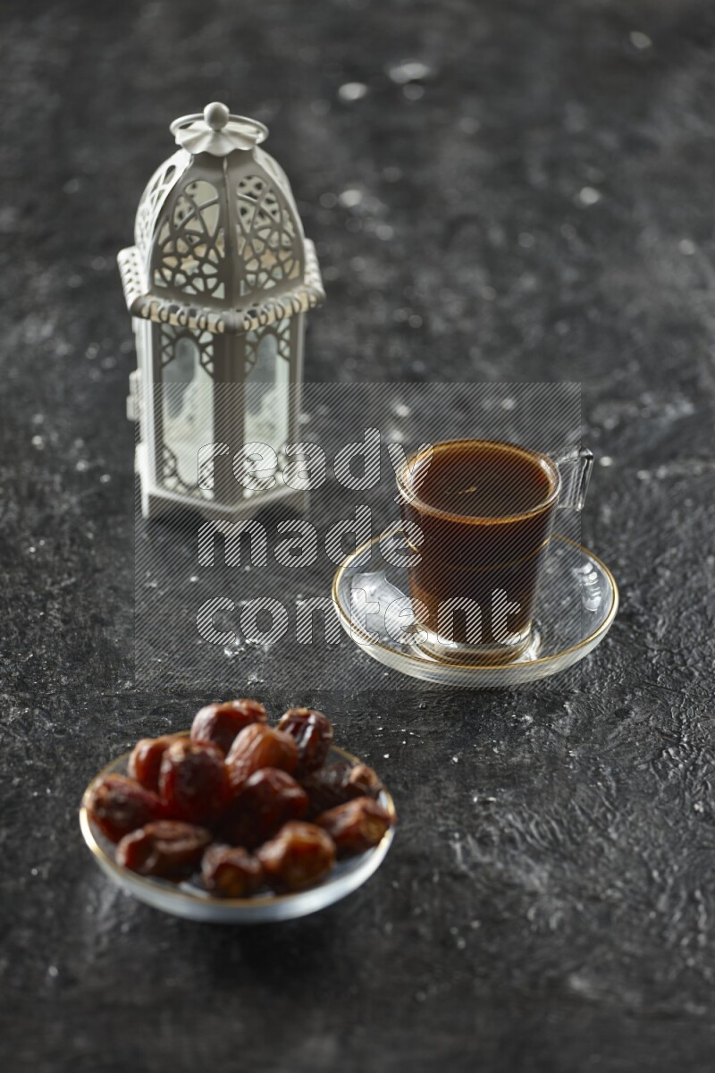 A white lantern with different drinks, dates, nuts, prayer beads and quran on textured black background