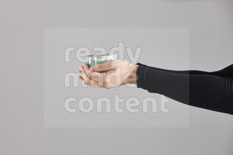 A woman in black abaya holding different pottery essentials in different positions