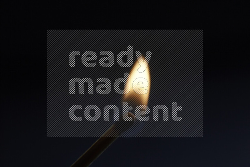 A burning matchstick isolated on dark backdrop