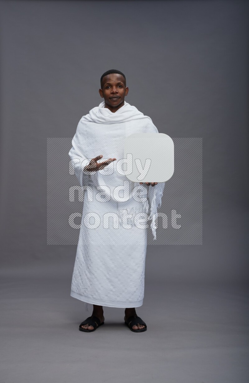 A man wearing Ehram Standing holding social media sign on gray background