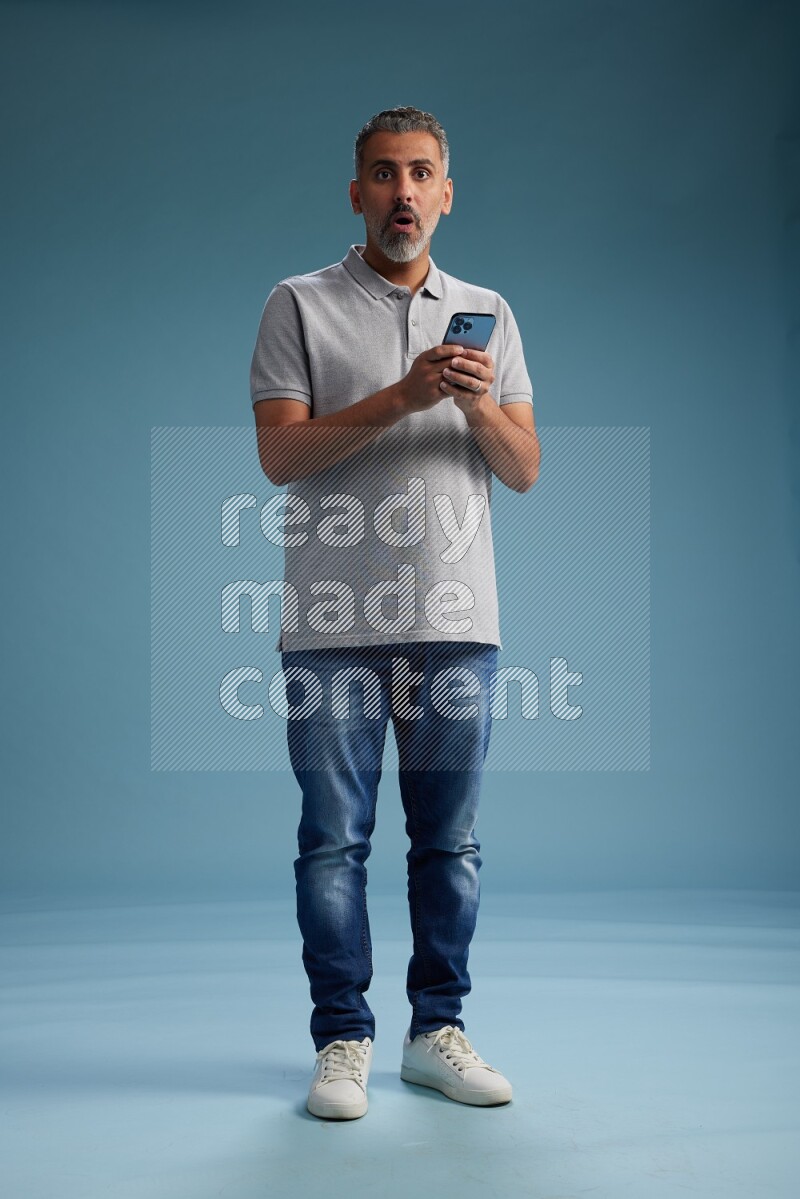 Man Standing texting on phone on blue background