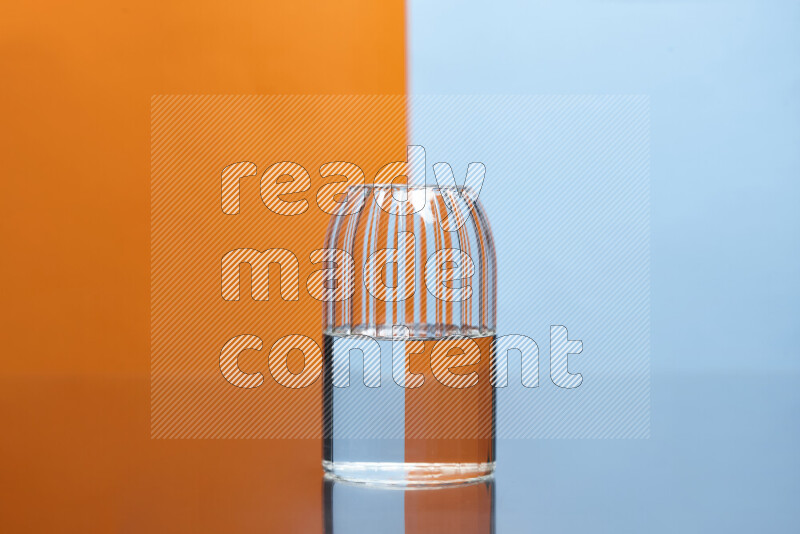 The image features a clear glassware filled with water, set against orange and light blue background