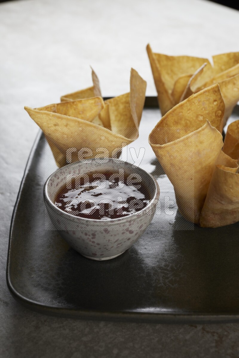 wonton cups with soy sauce ramkin on rectangle dark grey ceramic plate on grey textured counter top