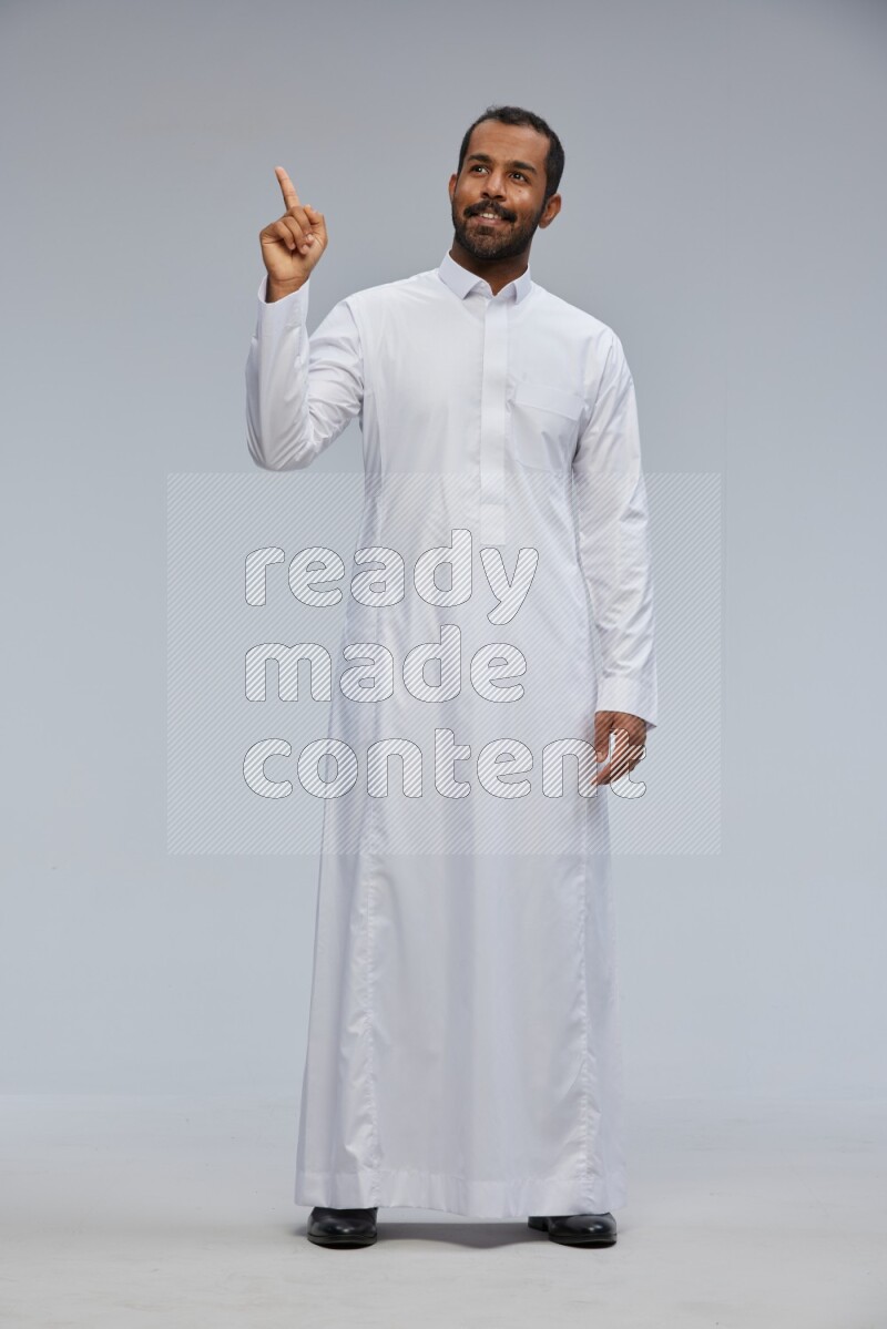 Saudi man Wearing Thob standing interacting with the camera on Gray background