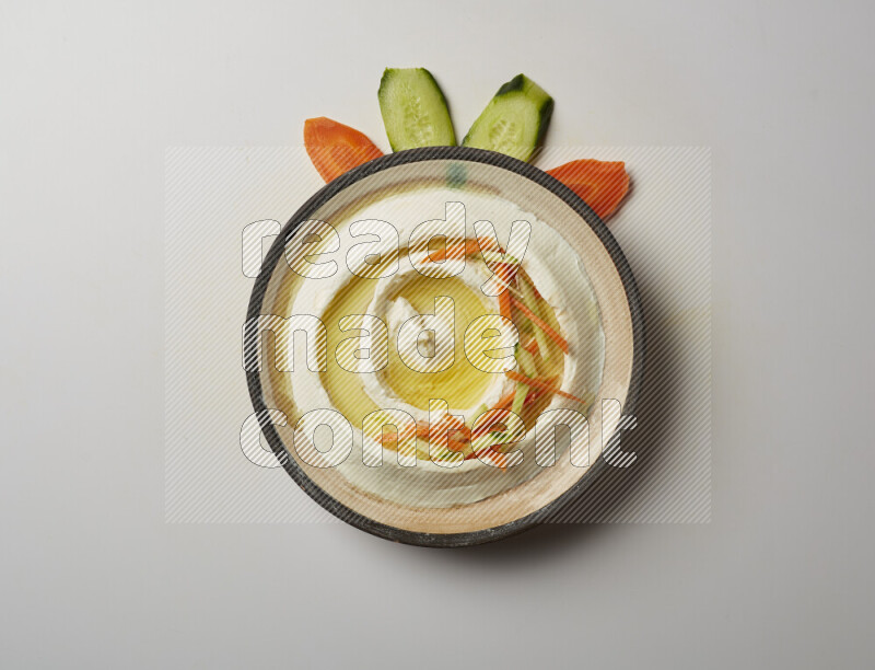 Lebnah garnished with sliced carrots &cucumber in a pottery plate on a white background