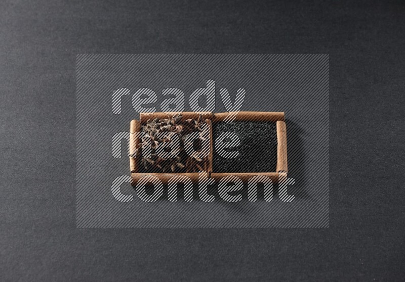 2 squares of cinnamon sticks full of black seeds and star anise on black flooring