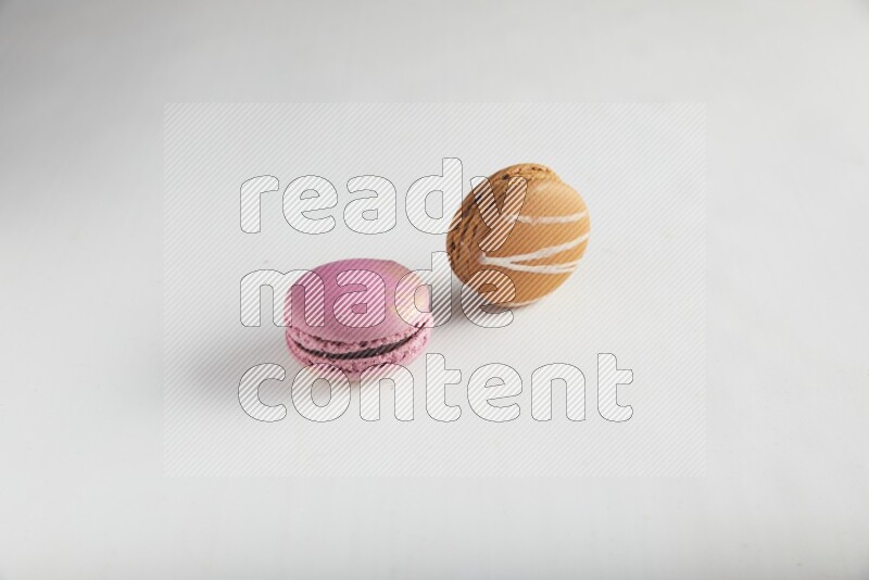 45º Shot of of two assorted Brown Irish Cream, and Purple Strawberry macarons on white background
