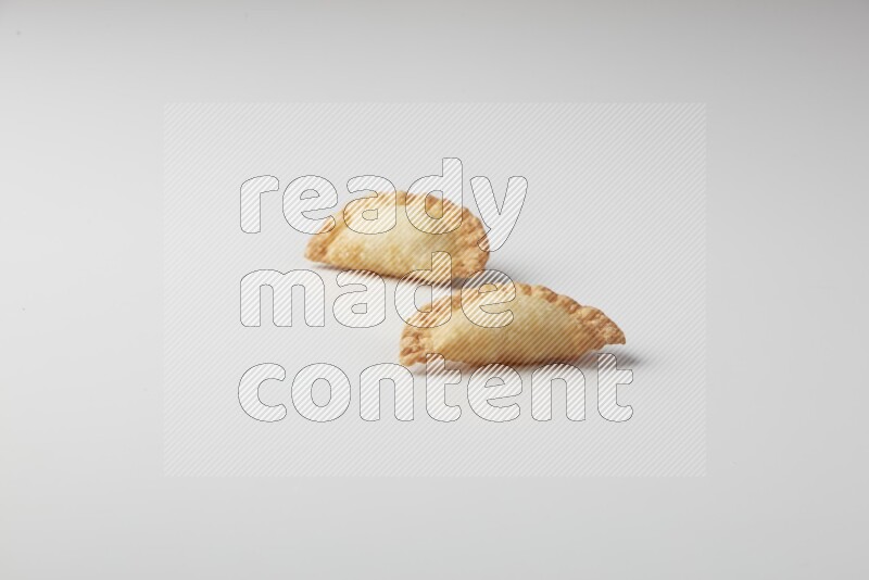 Two fried sambosas on a white background