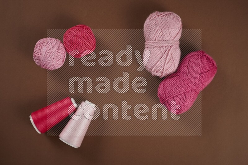 A pink collection of sewing and tailoring tools arranged on a brown background