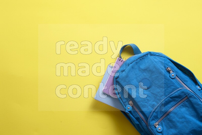 A blue school bag placed on yellow background